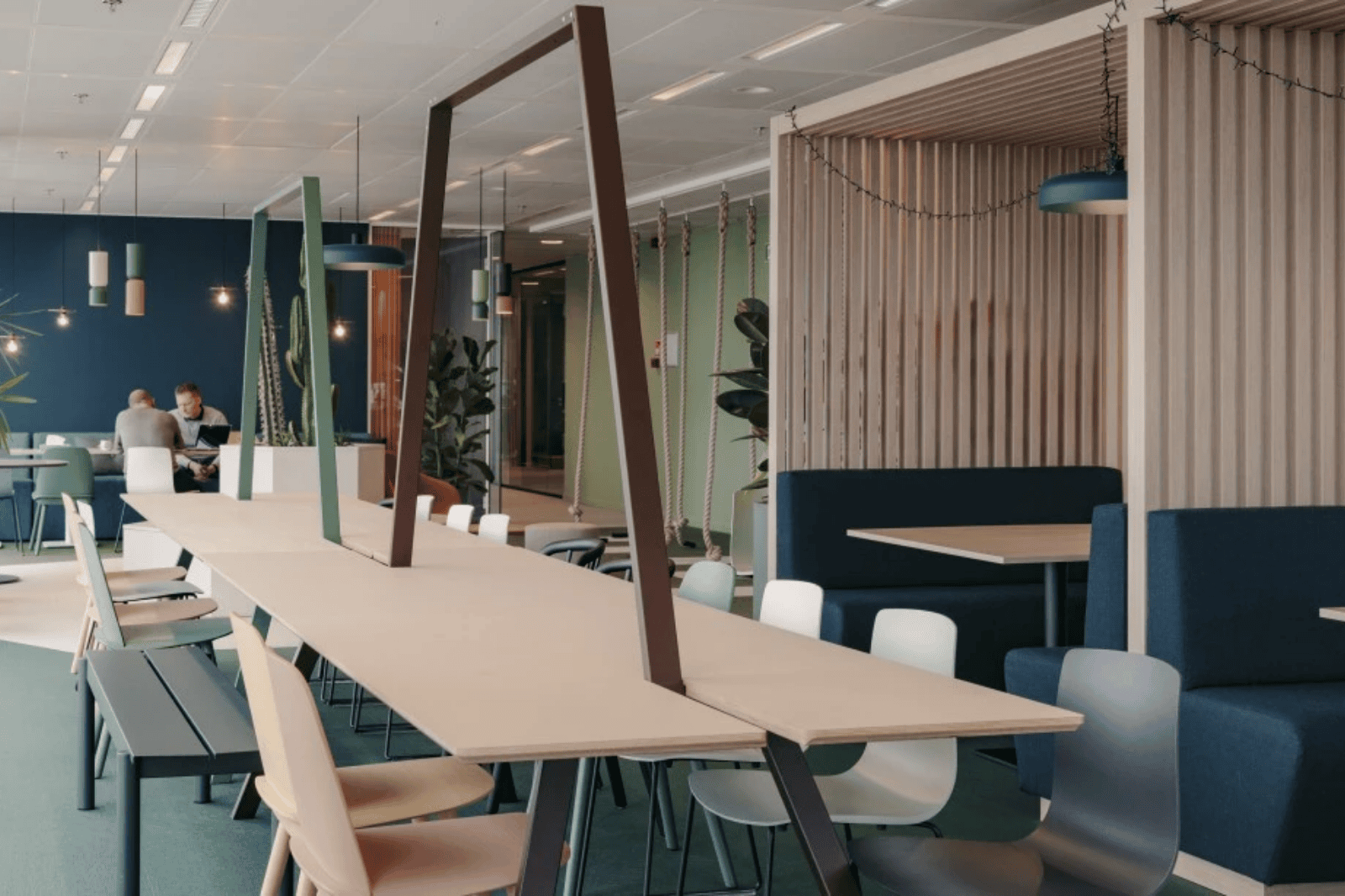 Creatieve meet&eat ruimte met lange tafel, hanglampen en moderne zitplaatsen