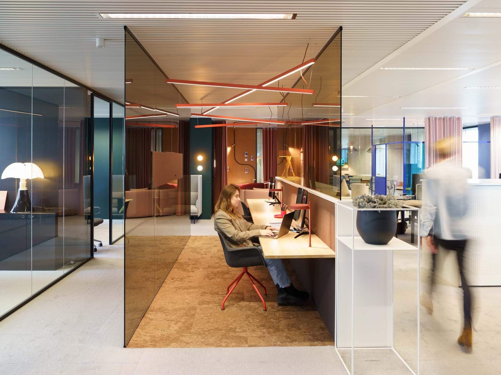 Medewerker werkt geconcentreerd aan flexwerkplek in open kantoorruimte met natuurlijke lichtinval