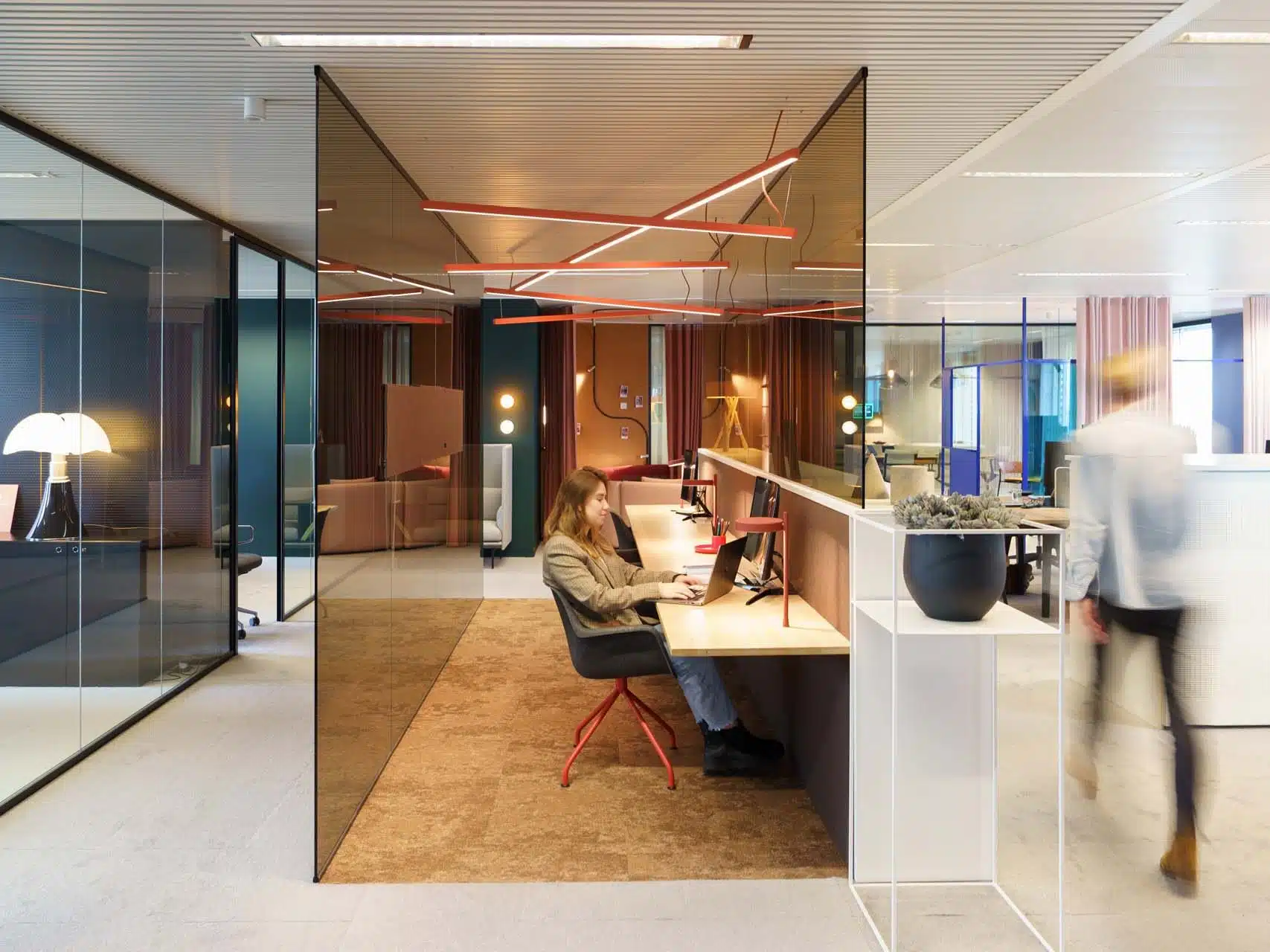 Medewerker werkt geconcentreerd aan flexwerkplek in open kantoorruimte met natuurlijke lichtinval