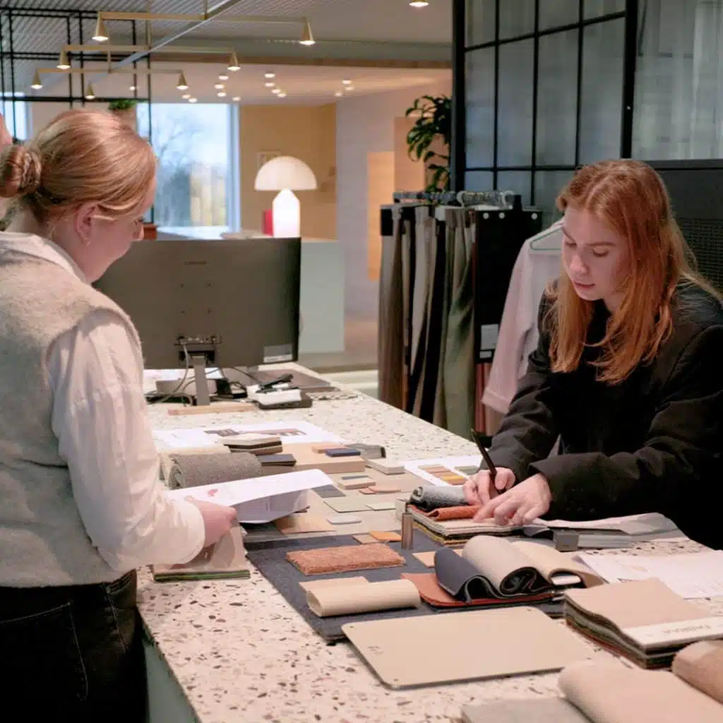 Twee interieurarchitecten bespreken materiaalstalen tijdens een kennismakingsgesprek met de klant