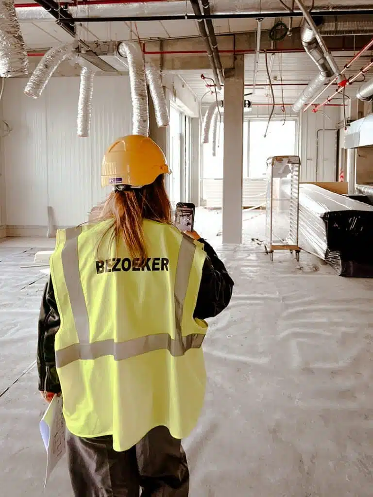 Projectmanager loopt door het kantoor tijdens een werfbezoek en bespreekt de voortgang