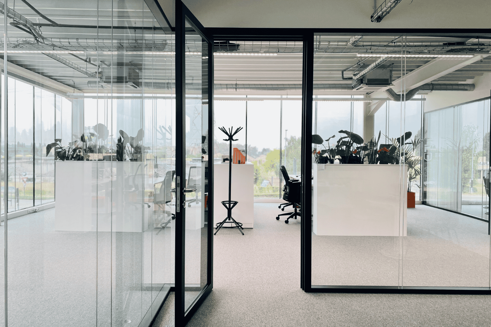 Vergaderruimte met glazen wand en zwarte stoelen rond een houten tafel
