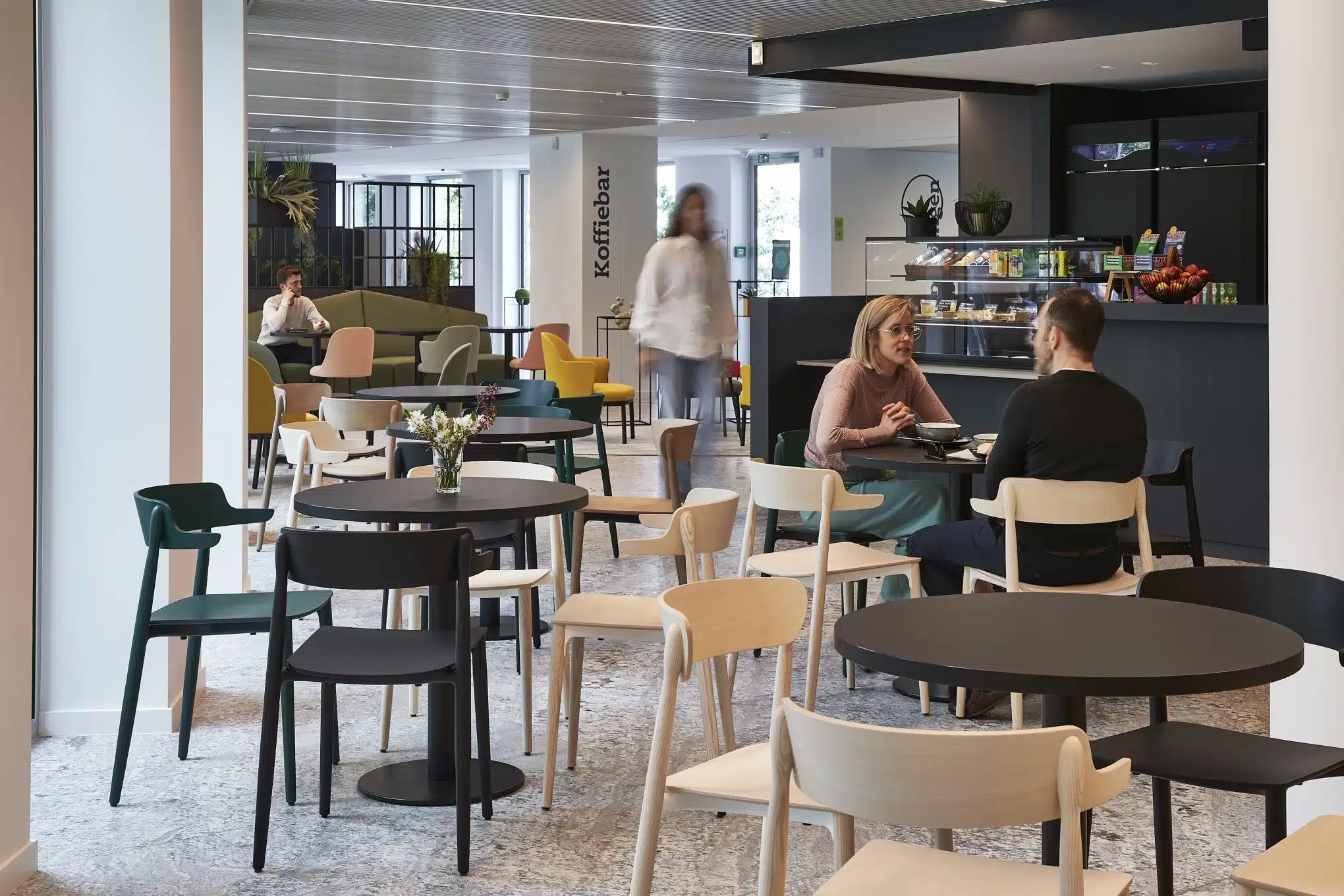 Gezellige koffiehoek met lichte kleuren en planten die bijdragen aan welzijn op de werkvloer