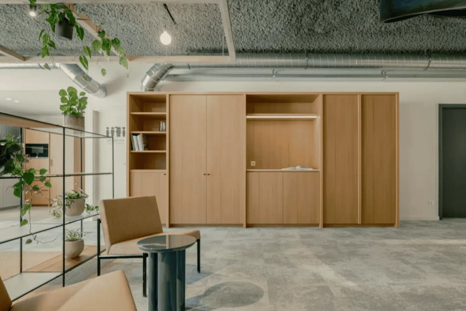 Loungehoek met houten kasten en veel groen in een modern kantoor