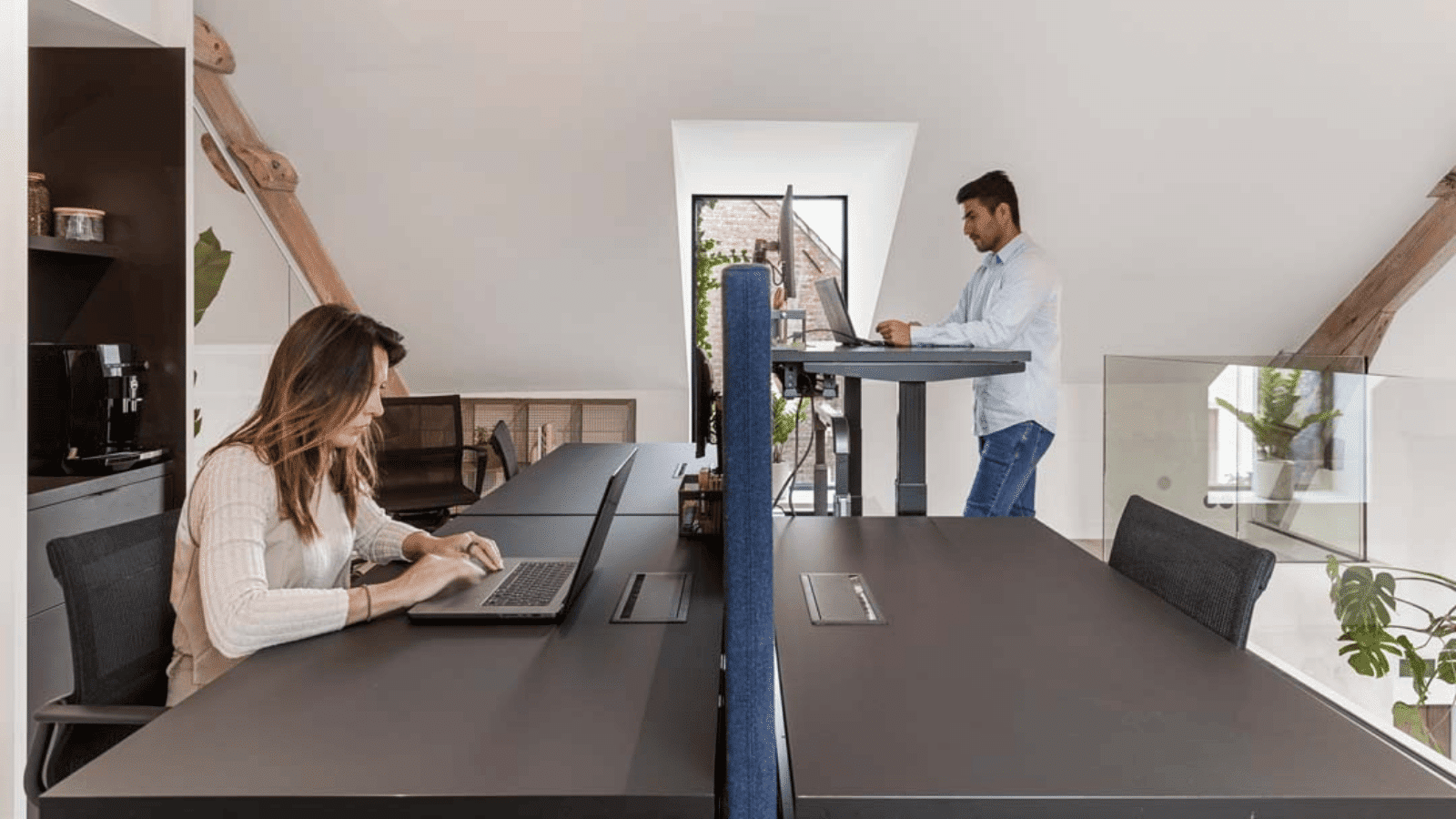 Collega’s gebruiken zit- en stawerkplekken in moderne flexwerkplek met veel daglicht