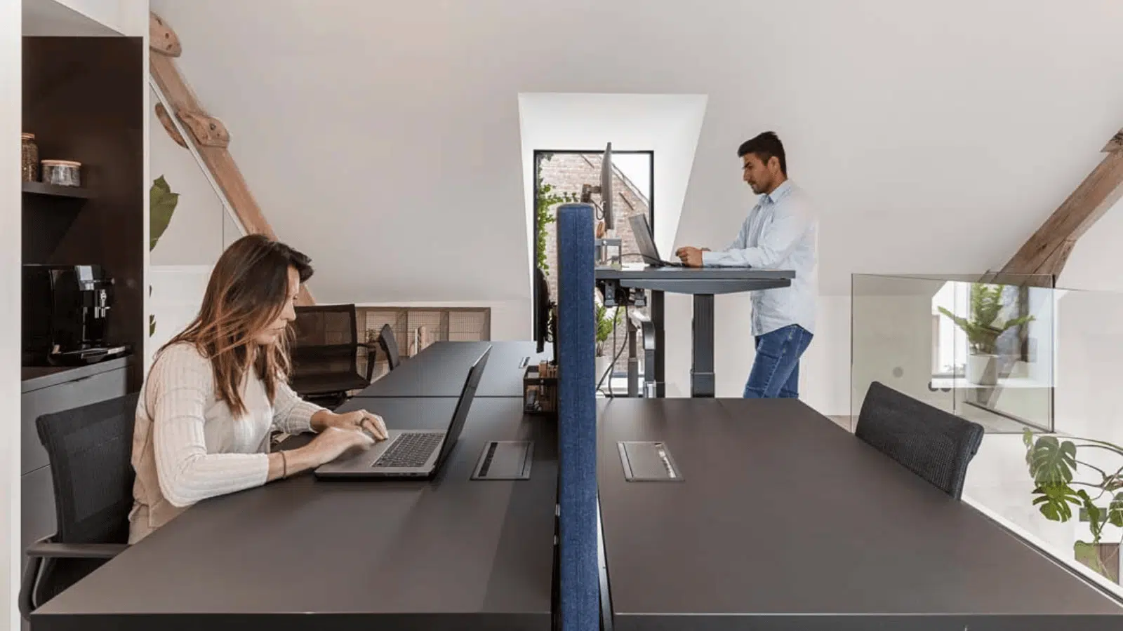 Collega’s gebruiken zit- en stawerkplekken in moderne flexwerkplek met veel daglicht