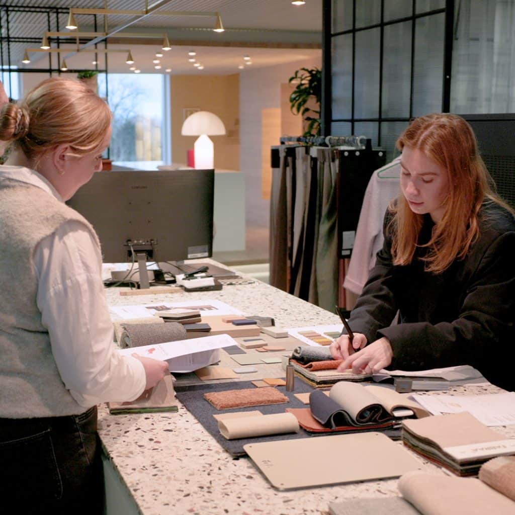 Twee interieurontwerpers bespreken materiaalstalen tijdens de voorbereiding van een kantoorrenovatie