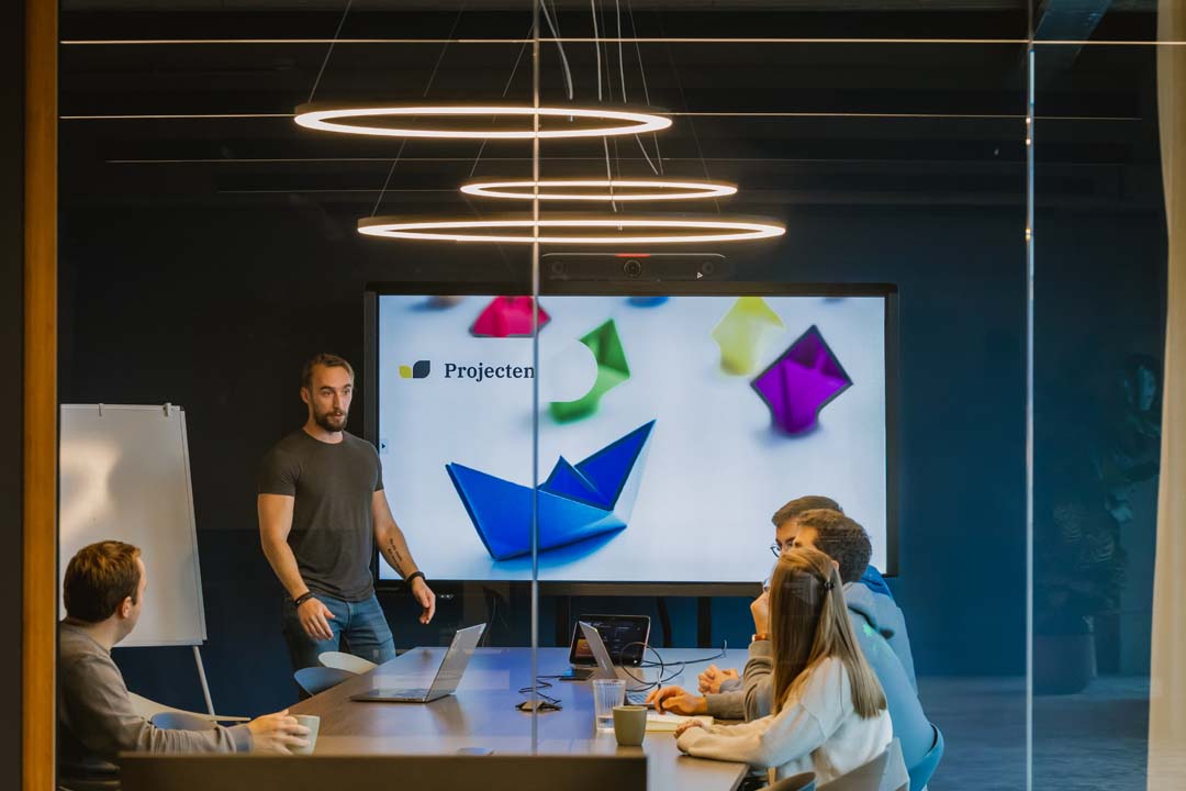 Moderne kantoorinrichting met vergaderruimte, designverlichting en presentatiescherm voor efficiënte meetings.