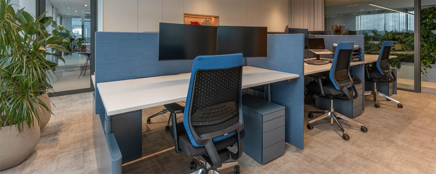 Flexibele werkplek aan het raam met hoogteverstelbare tafels voor geconcentreerd werken in een lichte ruimte