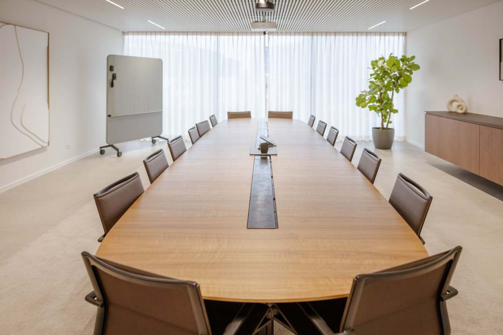 Lichte vergaderzaal in neutrale tinten met natuurlijk materiaalgebruik — een voorbeeld van hoe wit en beige een ruimte open en ruim laten aanvoelen.