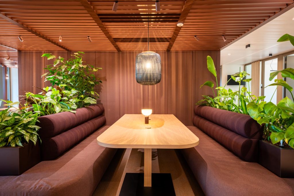 Rustige loungezone met zitbanken en veel planten voor informele ontmoetingen.
