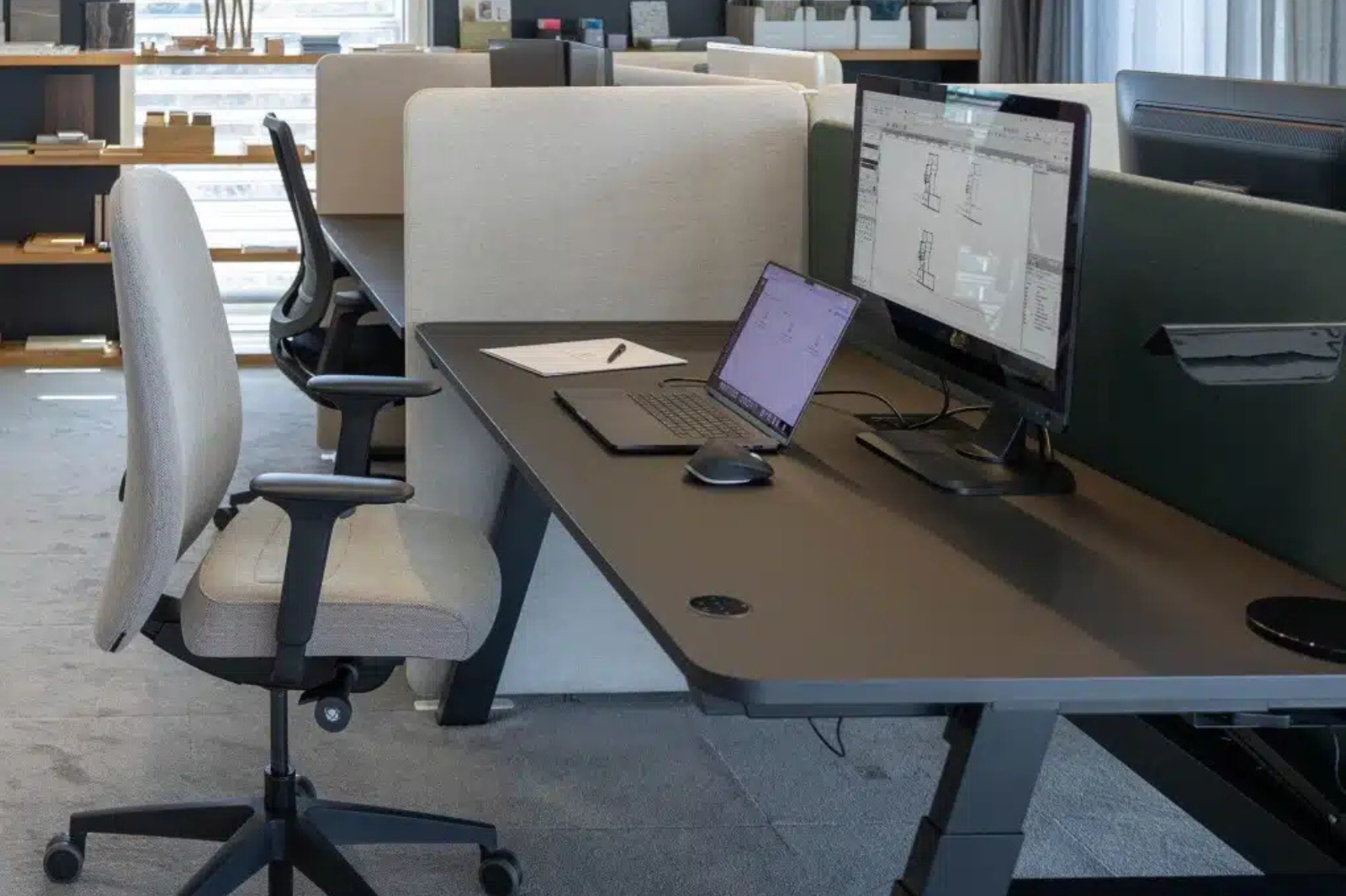 Een moderne beeldschermwerkplek met een in hoogte verstelbaar bureau en een ergonomische zadelkruk.
