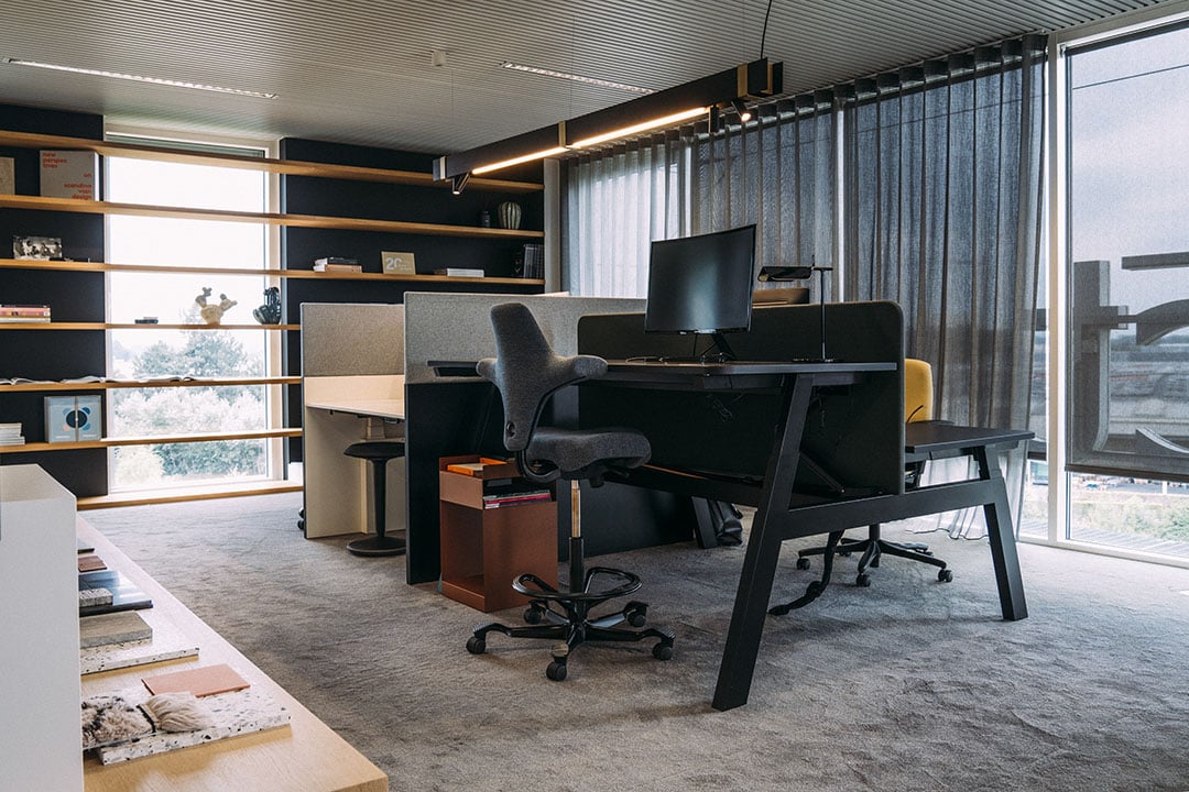 Een ergonomische werkplek waarbij een laptop naast een groter beeldscherm staat opgesteld voor een comfortabele werkhouding.
