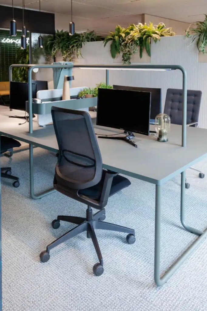 Ergonomische bureaustoel met mesh rugleuning aan een bureau met monitor en groene planten