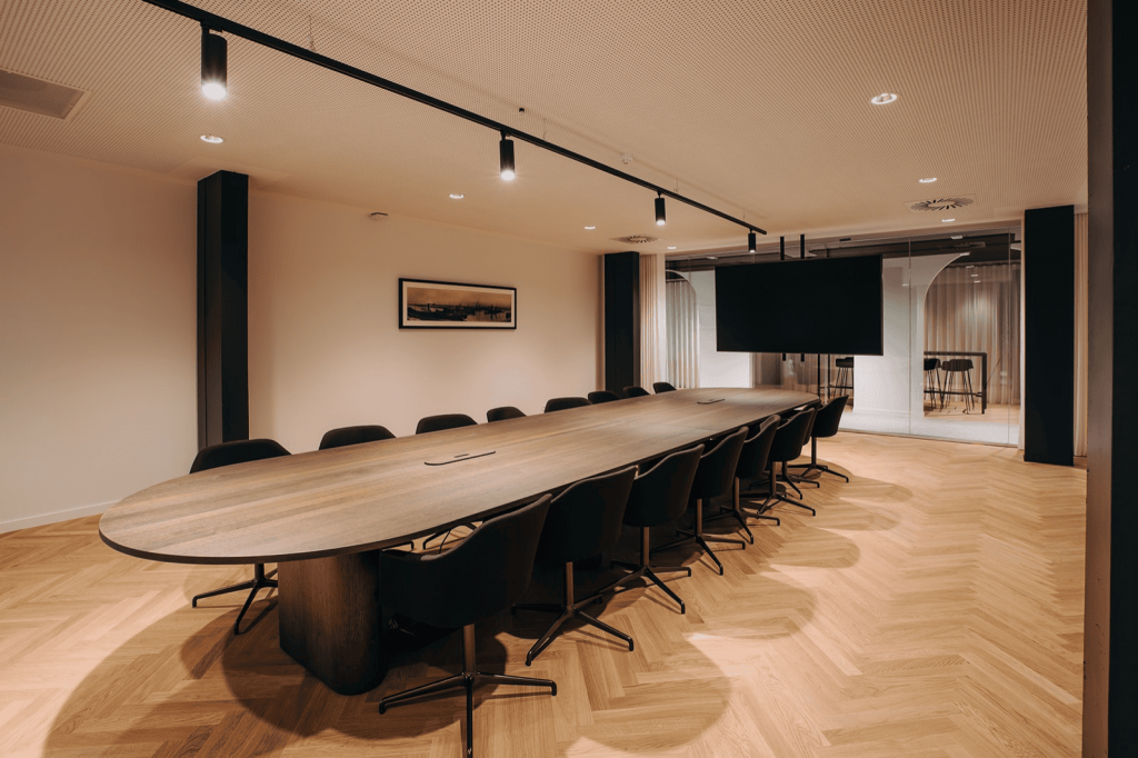 Grote vergaderzaal met lange tafel, stoelen en videoscherm voor teamoverleg