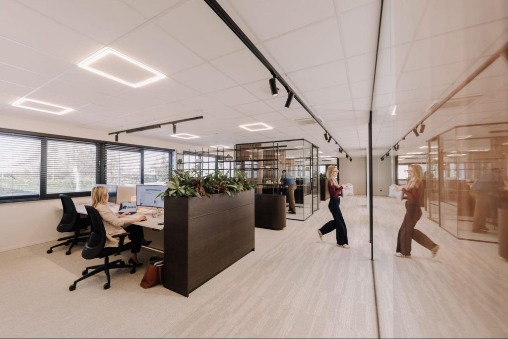 Open kantoorruimte met flexwerkplekken en glazen vergaderruimte voor hybride teams